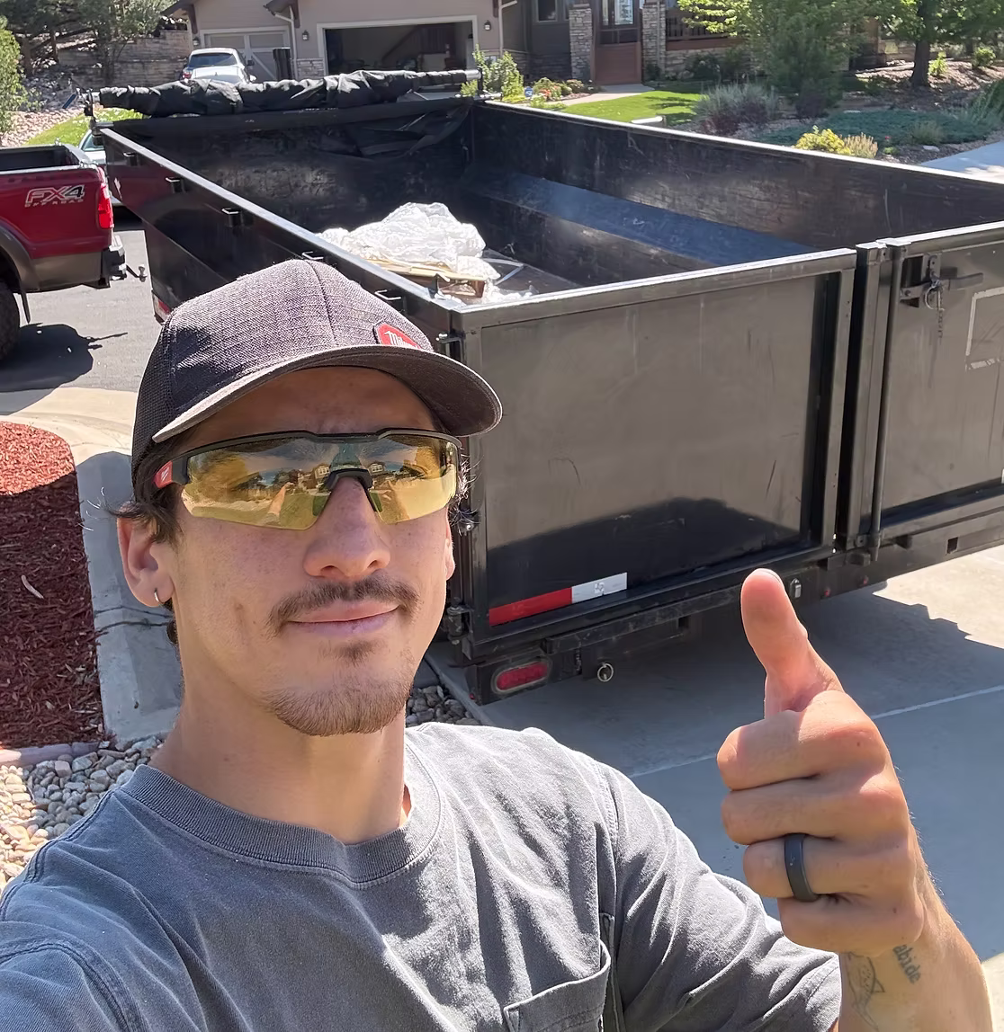 Ben from EZ Haulaway giving a thumbs up in front of the dump trailer at a jobsite